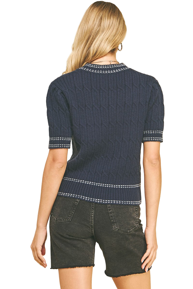 Person wearing a navy blue knitted top with white trim on a beige background