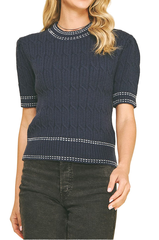 Woman wearing a navy blue sweater with white trim on a beige background