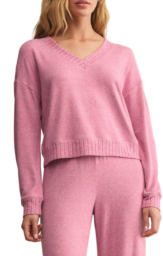 Woman wearing a pink sweater and pants against a beige background