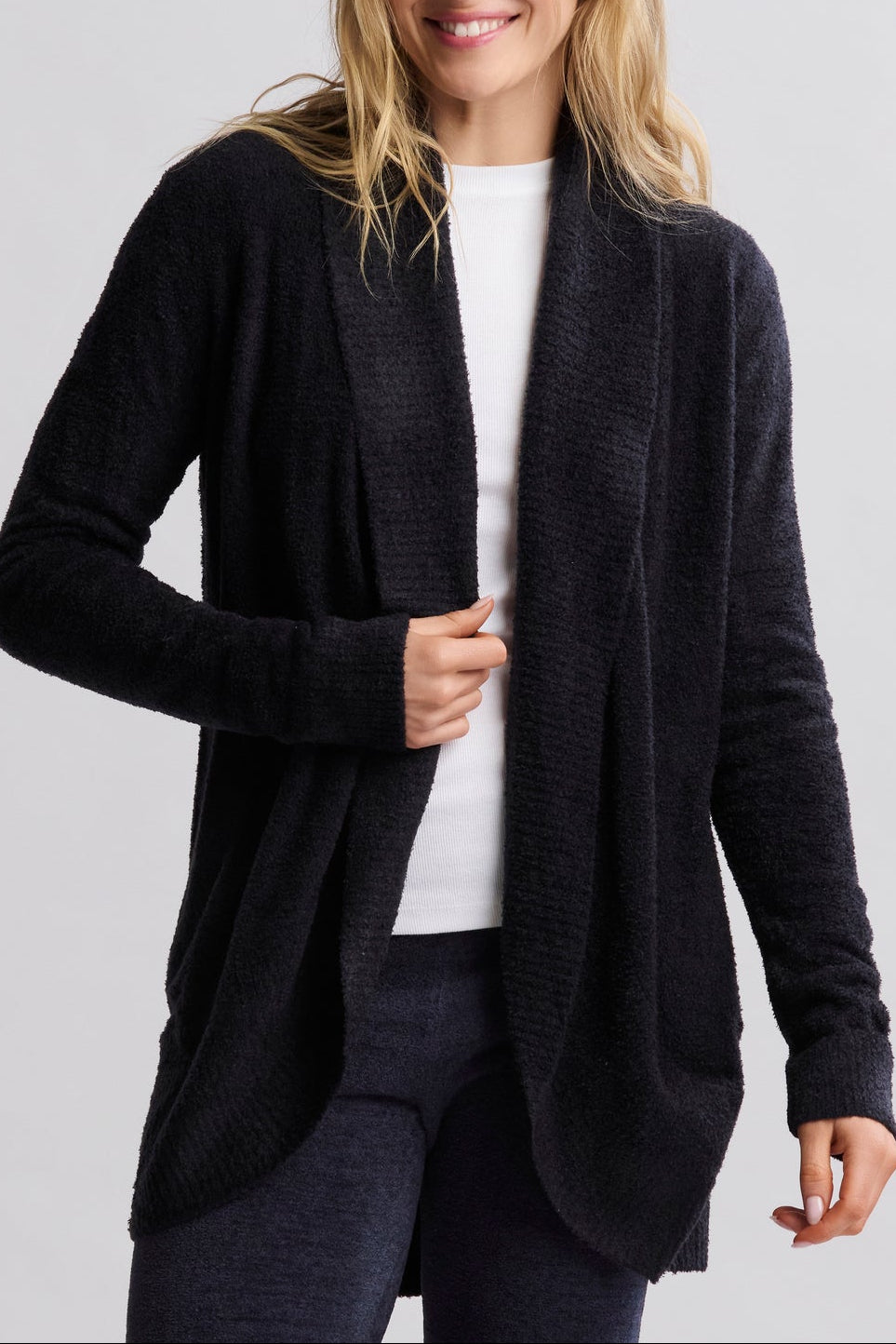 Woman wearing a black cardigan over a white shirt on a light gray background