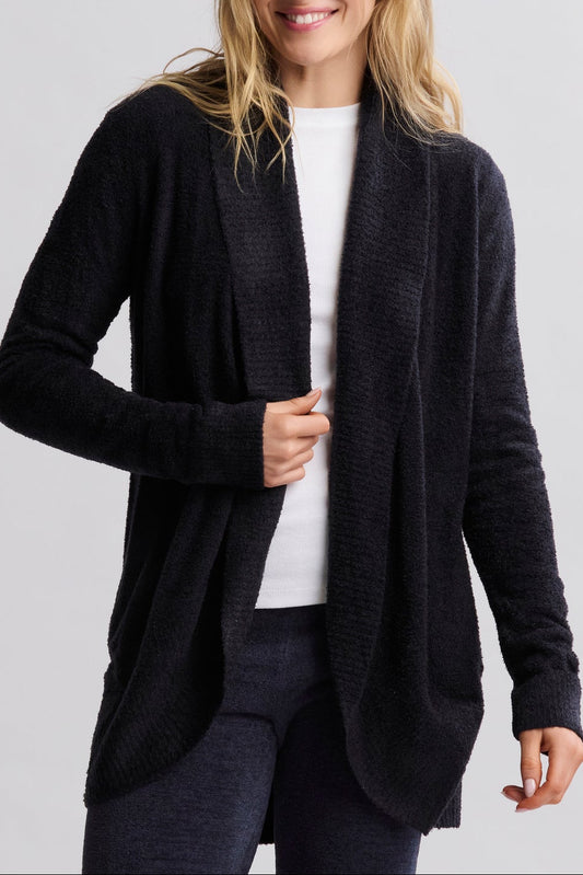 Woman wearing a black cardigan over a white shirt on a light gray background