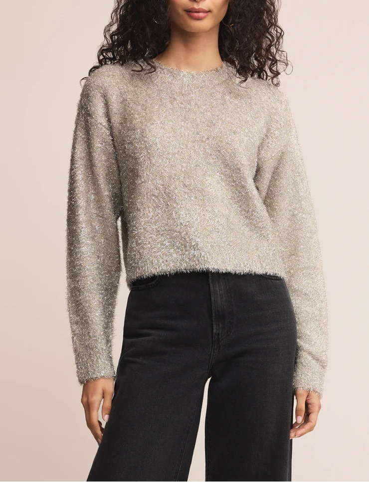 Woman wearing a textured sweater and black pants against a beige background